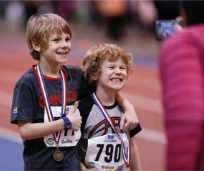 Kids smiling for a photo wearing track and field medals