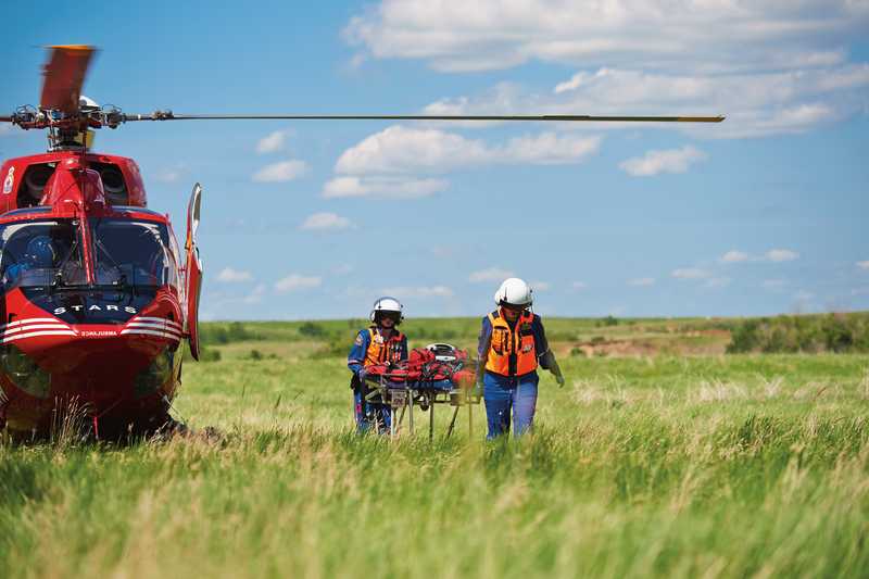 Stars helicopter paramedics carry a stretcher from their helicopter