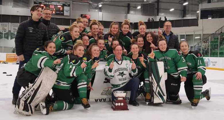 Saskatoon stars women's hockey team on ice wearing hockey equipment in front of a trophy